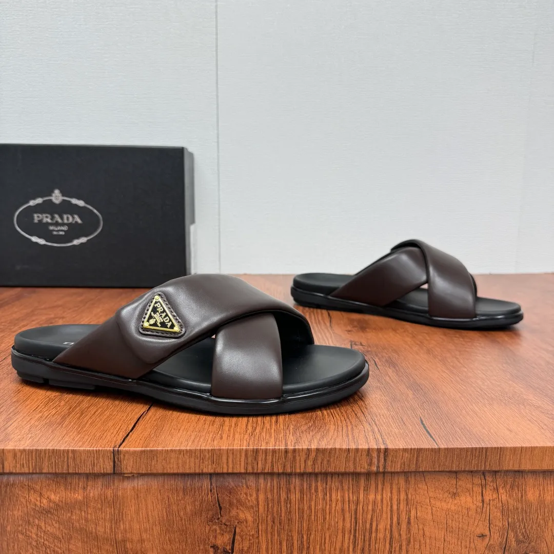 Batch 580 Prada/Prada's new men's leather cross slippers. Velcro closure can finely adjust the size. Calf leather light luxury slippers. Thick soft calf leather wraps the upper. Fat but soft rubber lazy style, soft and comfortable, excellent foot feel. Genuine leather bottom layer, cross style, with a Velcro closure buckle, easy to adjust the appropriate size, and a perfect fit for the wearing experience. The enamel gold triangle logo highlights the brand's classic features. Lightweight rubber thin sole, high foot comfort! Complete package! Size: 39-40-41-42-43-44-45 Leather shoe size Item number: 2X7132 Brown